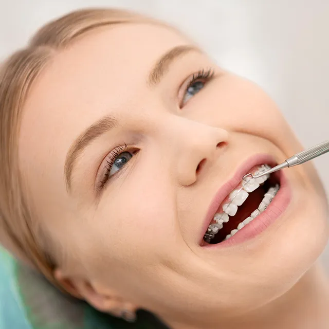 Frau lächelt während einer Zahnspangenuntersuchung beim Zahnarzt.